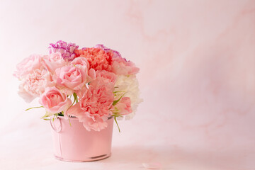 Mather's day concept. Colorful carnation and pink rose in a pink bucket