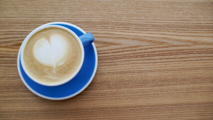 Macro photo cup of coffe cappuccino or late with hert on foam on wood tecture table in caffe. City bustle outside the window