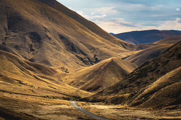 Road leading through Lindis Pass against sky, New Zealand