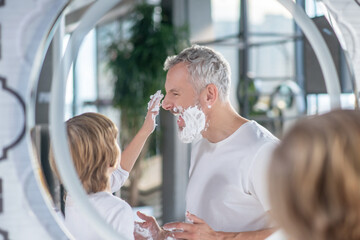 Boy and a man playing with shaving foam