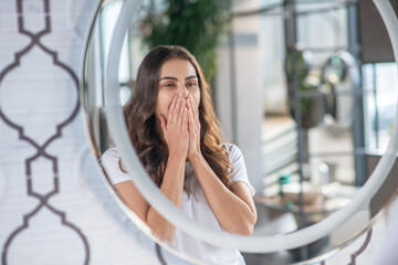 Sleepy young woman yawning near the mirror - Powered by Adobe