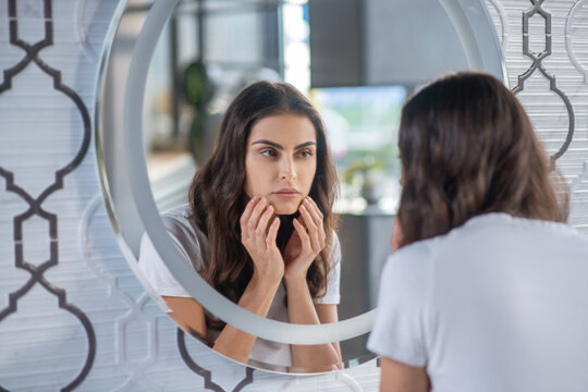 Woman looking at her reflection in the mirror