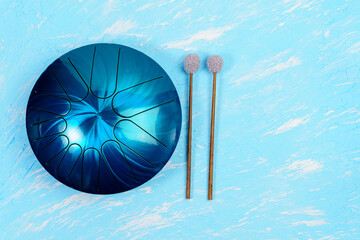 hang musical instrument, glucophone. metal tongue drum, blue background. top view copy space