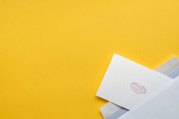 Handmade postcard with mark of lips from envelope on yellow background