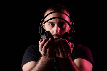Portrait of DJ musician with beard holding professional headphones in front of him. International DJ Day