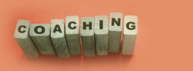 Coaching word on wooden blocks on aqua blue background. Personal and business achievements concept