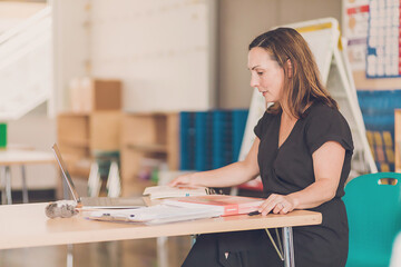 Female teacher organizing notes in her 1st grade classroom.