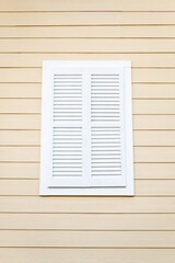 White Louvered Window Shutter on a Cream Wooden Building