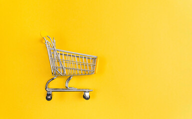 mini shopping cart on yellow background top view. Shopping concept. space for copying text