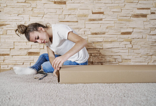 Front view of caucasian girl opening a brown paperboard box with