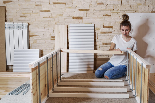 Front view of a young blonde girl screwing a screw with a screwd
