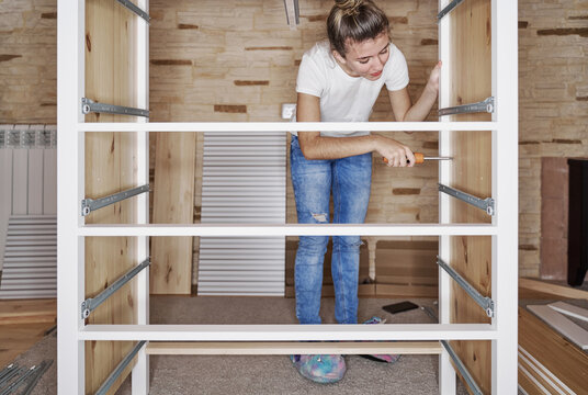 Front view of a young blonde girl screwing a screw with a screwd