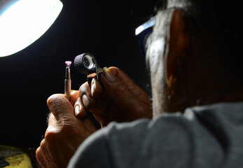 Person looking at gemstone with magnifying loupe
