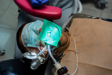 dentistry under general anesthesia. Dentist treats a patient with rubber dam
