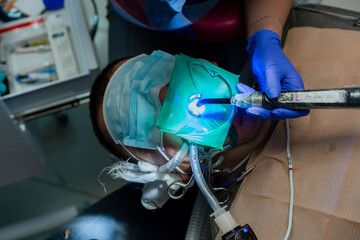 dentistry under general anesthesia. Dentist treats a patient with rubber dam
