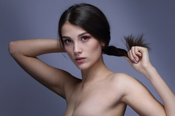 Portrait of a beautiful girl with bare shoulders on a gray background