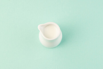 Small bowl of milk on teal background top view
