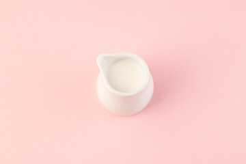Small bowl of milk on pink background top view