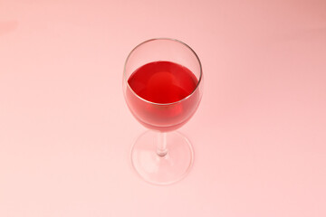 Red wine glass on pink background top view