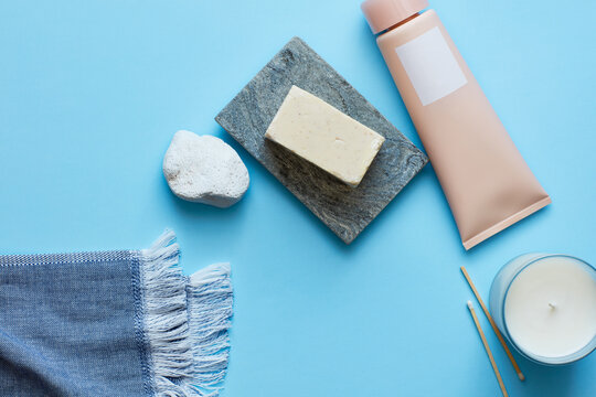 Soap, cream, candle on turquoise surface