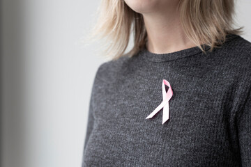a young woman is wearing a pink October ribbon on her sweater