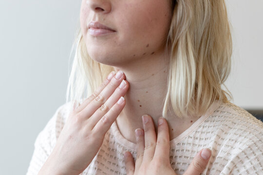 a young woman feels her thyroid gland