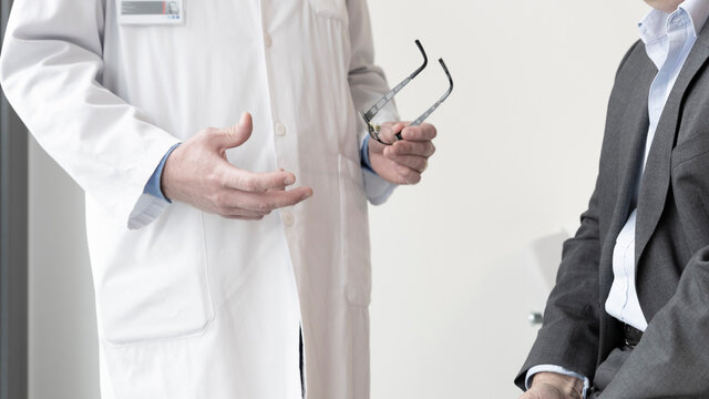 a doctor discusses with a patient sitting on an auscultation bed