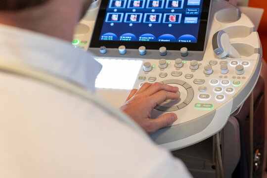 shot of a caregiver's hand, using the keyboard of an ultrasound