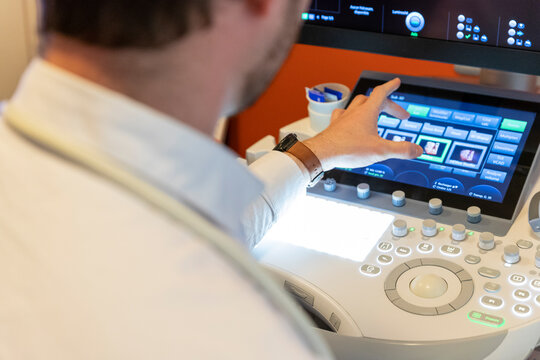 shot of a caregiver's hand, using the keyboard of an ultrasound