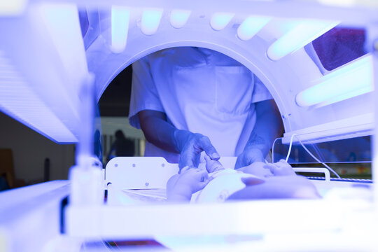 newborn in an incubator. A nurse taking care of the baby