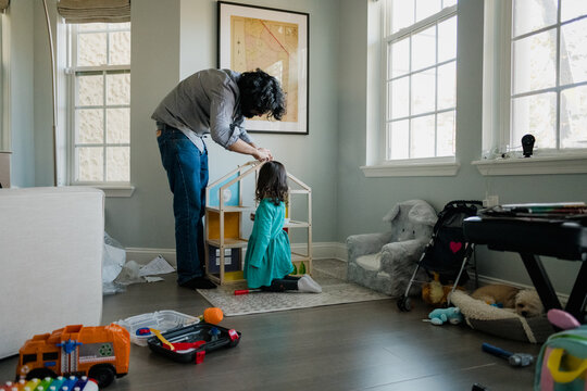 Dad And Daughter Assembling Dollhouse In Messy Room