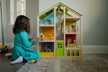 Young child playing with dollhouse