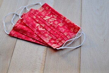 Red color mask with Chinese Luck character in different writing styles on wooden background.