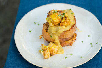 Vegan french toasts with peanut butter, syrup and banana on a white plate.
