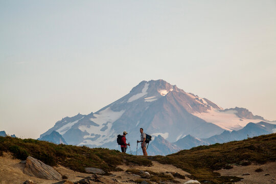 Two hikers climb towards the summit of Glacier Peak at dawn.