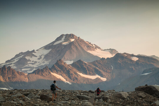 Two hikers climb towards the summit of Glacier Peak at dawn.