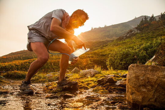 A man fills up his water bladder in a stream, Glacier Peak Wilderness