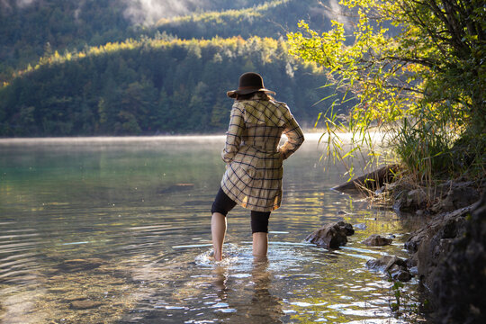 A lady cautiously wading through an alpine lake in Germany
