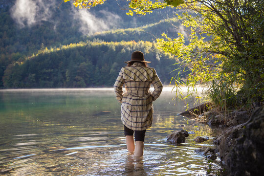 A girl walking barefoot by the waters edge in an alpine lake
