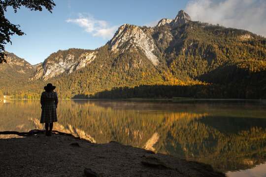 A woman stands in the shadows of a mountain by the lake in Germany