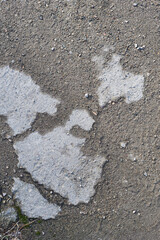 Grey texture of old broken asphalt road or wall big abrasions cracks holes on the surface pebbles cement in Sofia, Bulgaria, Eastern Europe