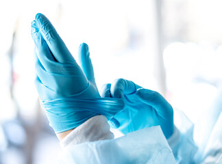 Medicine and Surgery theme: doctor putting on protective blue gloves