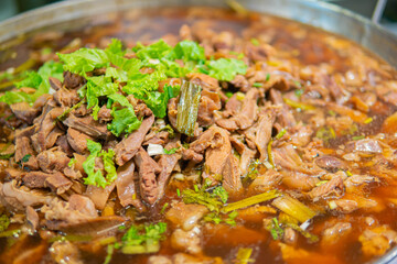 Macro close up shot of Pork stewed in the gravy with green coriander leaves on top and soup. Thai food.