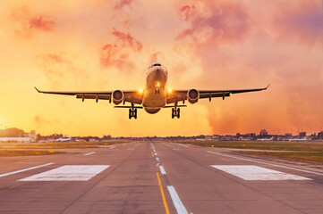 Fototapeta na wymiar Commercial airliner passenger plane fly down over landing at sunset.