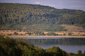 spring landscape with forest near the lake at sunset. cultivated fields