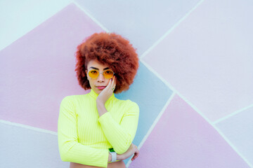 portrait of gorgeous woman with afro hair and yellow sweater over pink wall