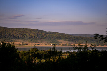 spring landscape with forest near the lake at sunset. cultivated fields