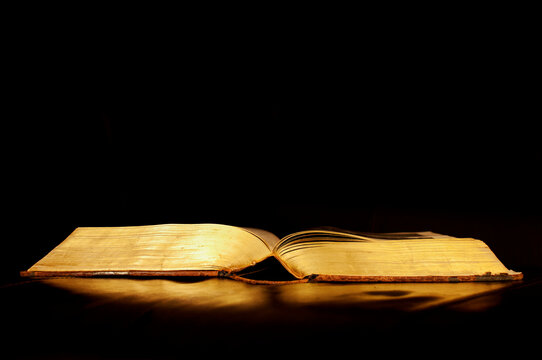 One open book on reflective black surface