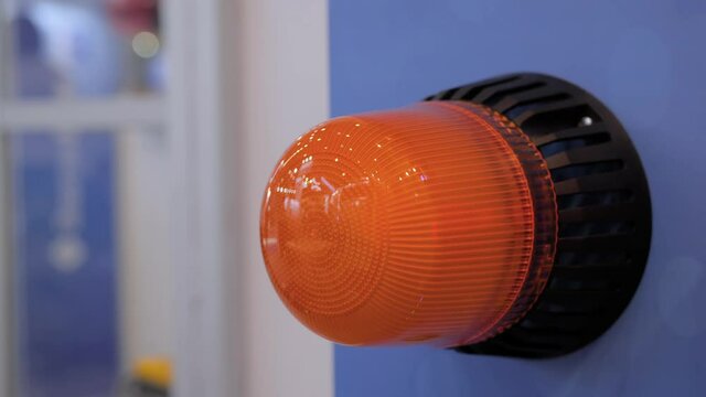 Close up of alarm lamp signal warning flashing lights on blue wall for industrial machinery at emergency, support and services exhibition. Danger, legal, alert light, attention and hazard concept