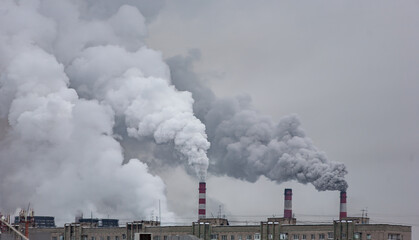 industrial chimneys with heavy smoke causing air pollution on the gray smoky sky background